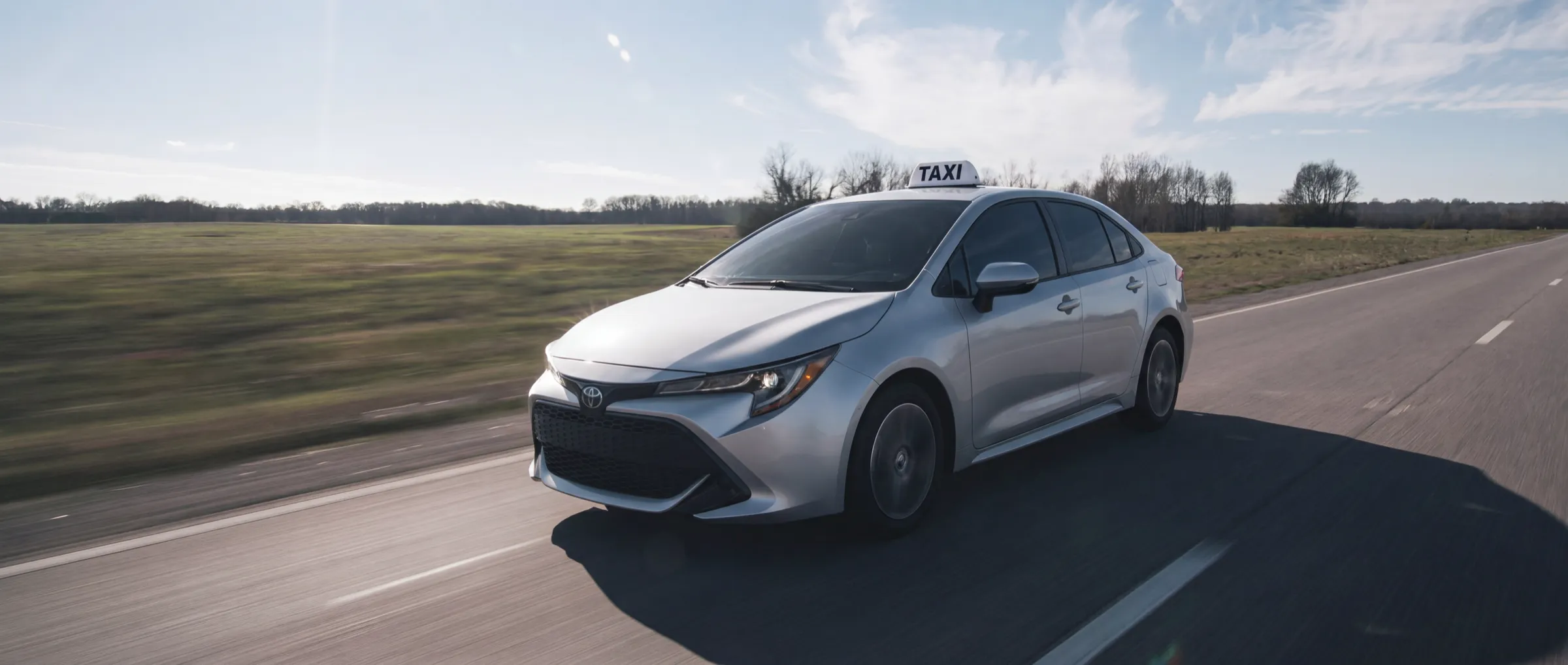 Kierowca Flick Partner w taksówce — Toyota Corolla z kogutem TAXI na drodze pod Łodzią